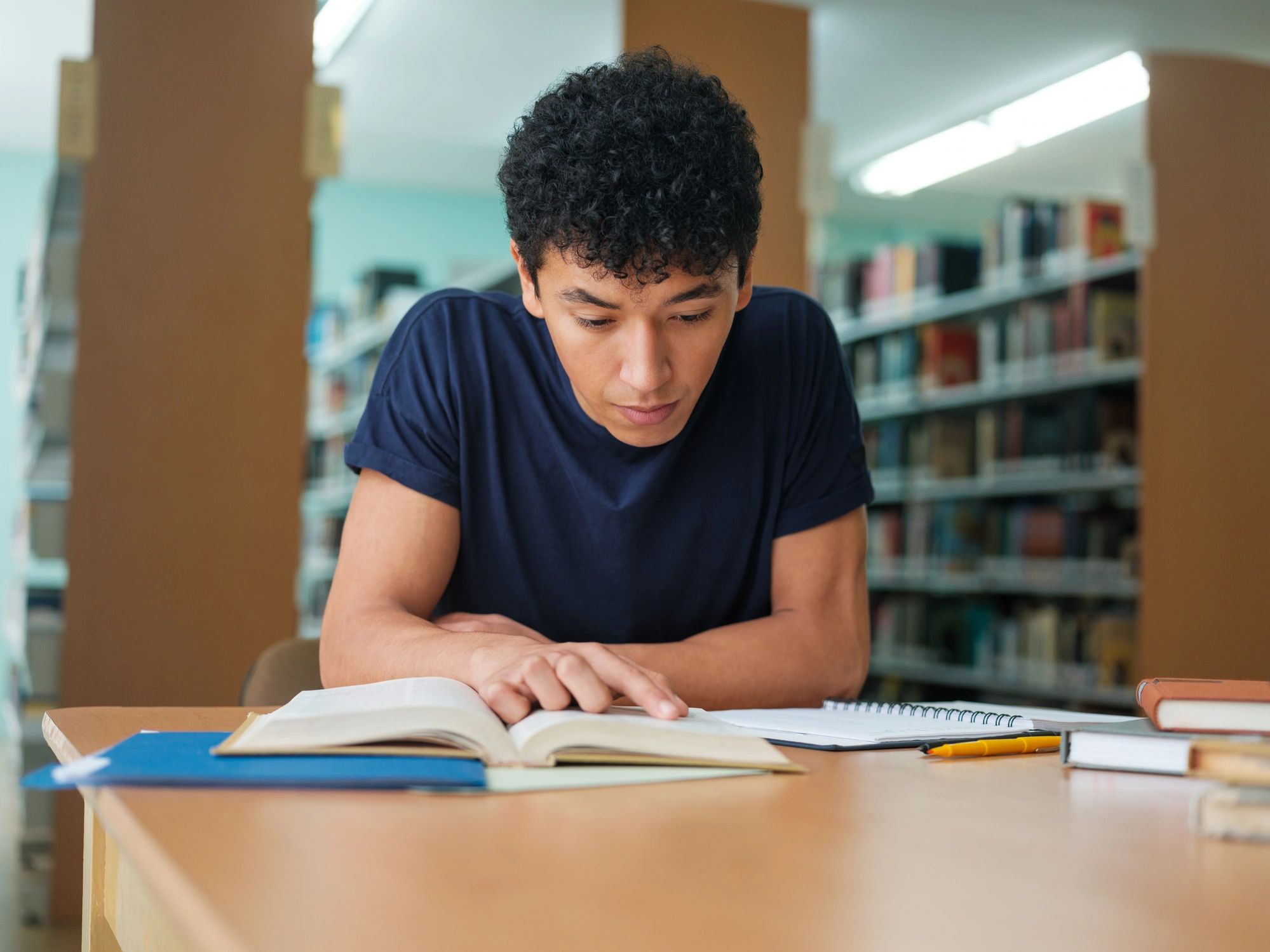 Student studying with a book in a library